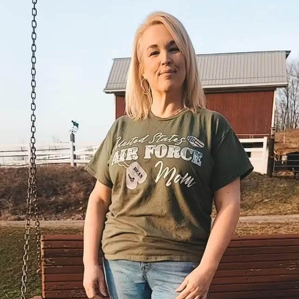 air force mom posing and showing her new graphic design t shirt in front of her house